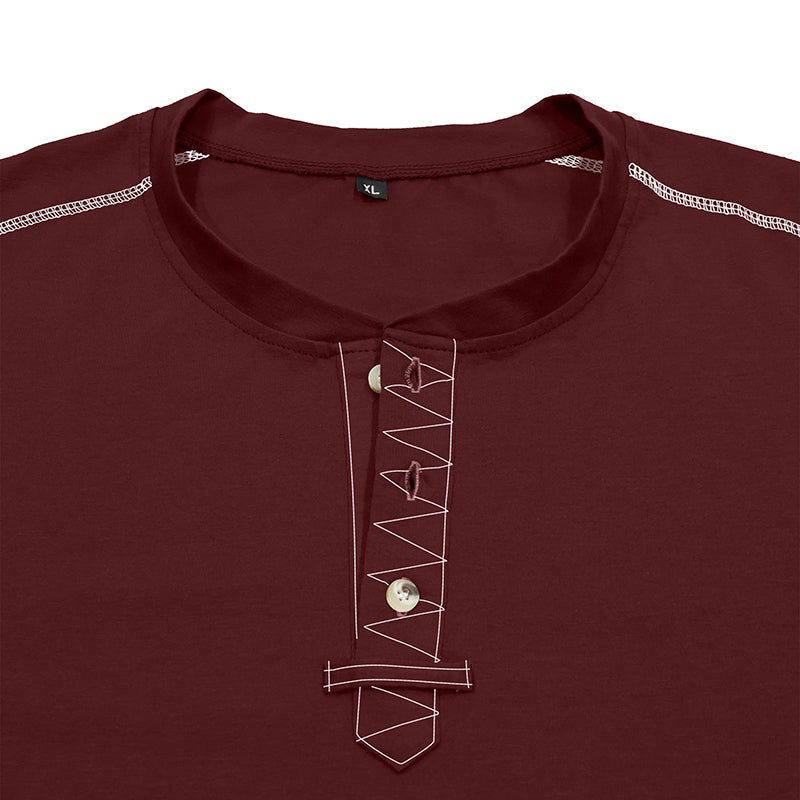 A close-up of a maroon long-sleeve tunic shirt featuring a decorative white geometric embroidered pattern down the center placket, with two buttons and a small silver-toned pendant.